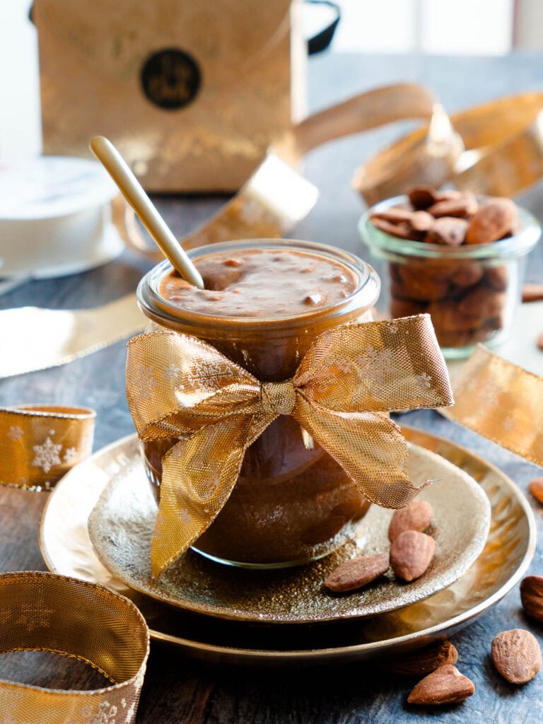 Gebrannte-Mandel-Mus im kleinen Gläschen mit goldener Schleife als selbstgemachtes Geschenk aus der Küche.
