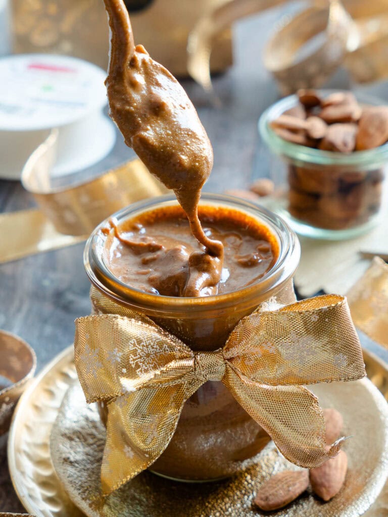 Ein Löffel voll mit cremigem, veganem Gebrannte-Mandel-Mus mit Mandelstückchen.